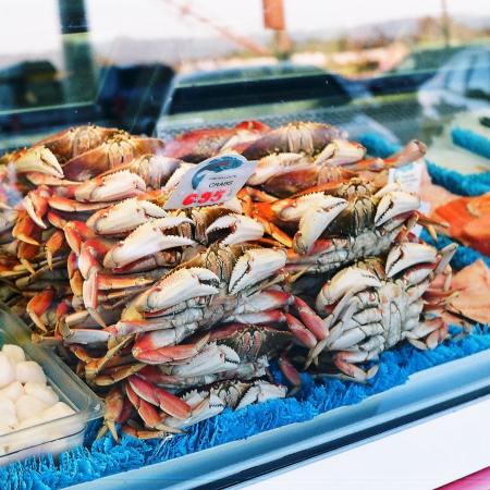 A pile of crabs sitting behind glass at a seafood market
