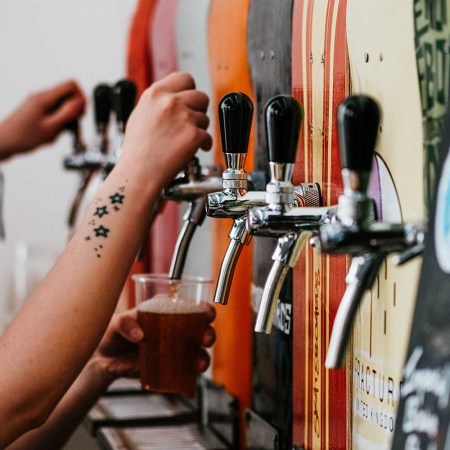 two bartenders grabbing beer from taps