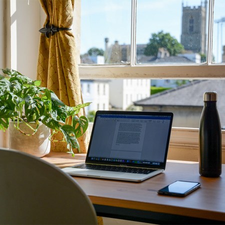 A laptop computer sitting on a desk by a window in a home