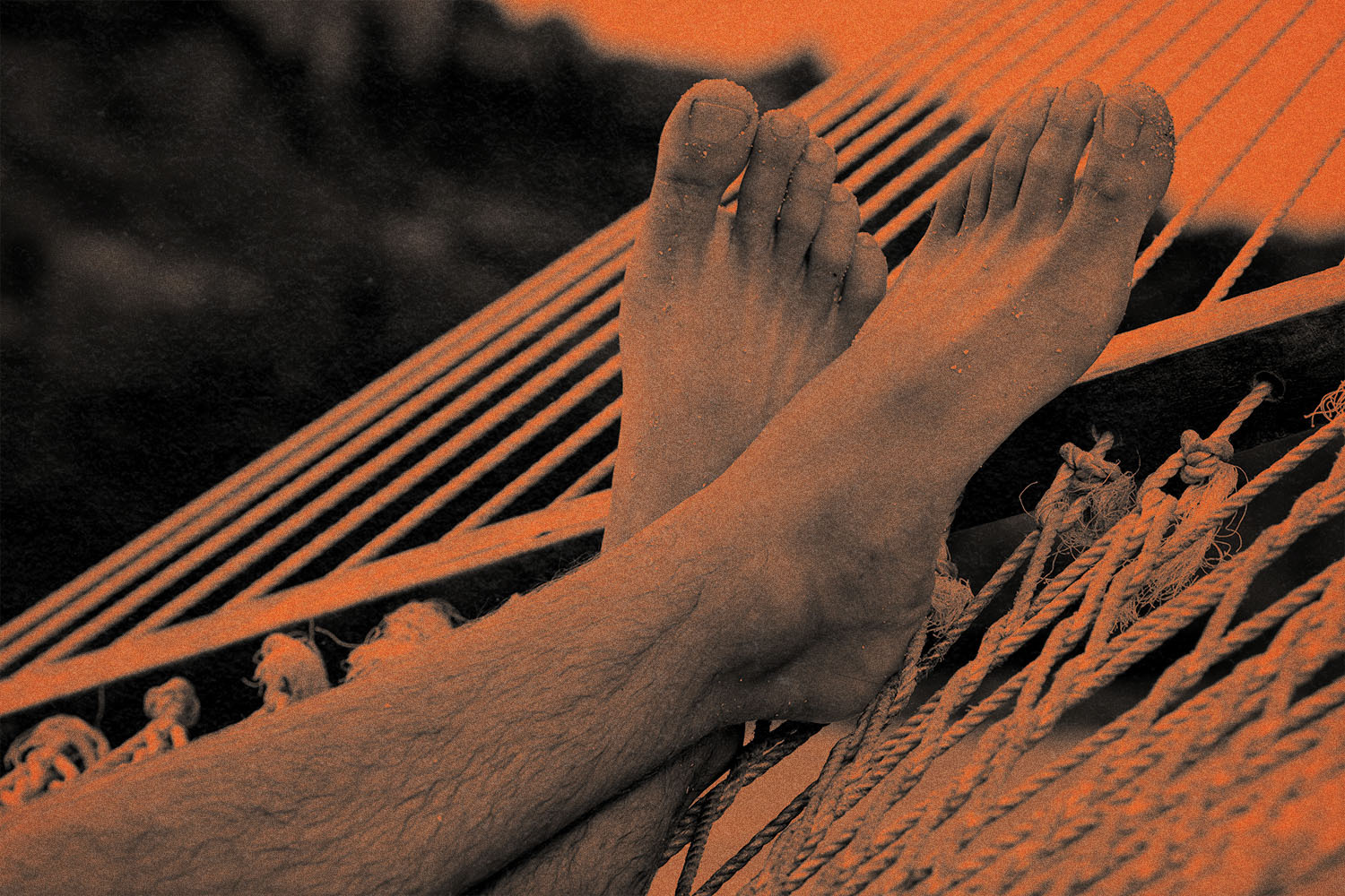 A pair of feet resting on a hammock.