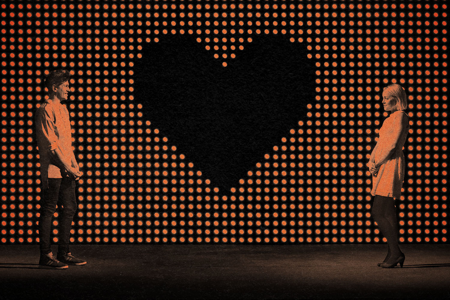 Two people stand far apart from each other on either side of a giant black heart background