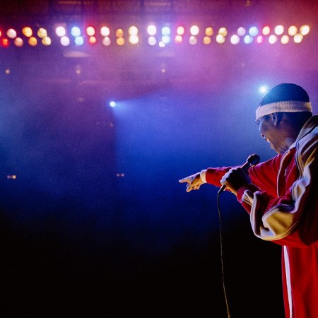 Rapper on stage under blue and purple stage lights, pointing out at audience