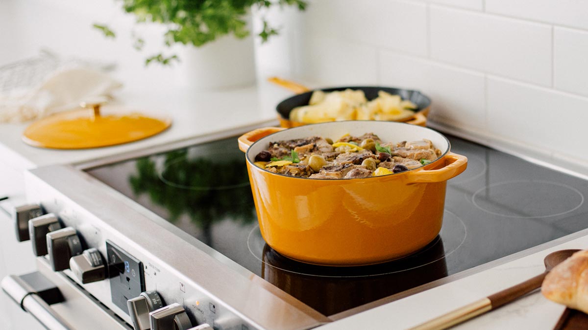 The Milo Dutch oven and skillet, in dijon yellow, sitting on a stove. We tested and reviewed the cookware.