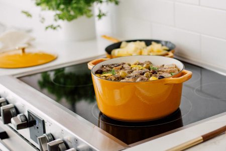 The Milo Dutch oven and skillet, in dijon yellow, sitting on a stove. We tested and reviewed the cookware.