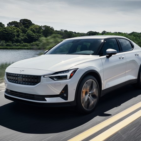 The Polestar 2 EV driving down the road next to a lake