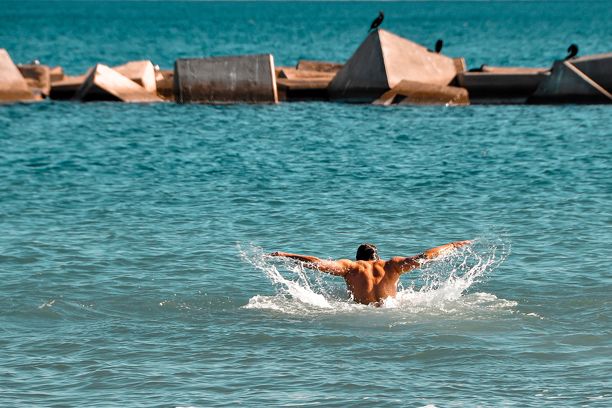 A pair of swimmers in the open ocean swimming toward the horizon