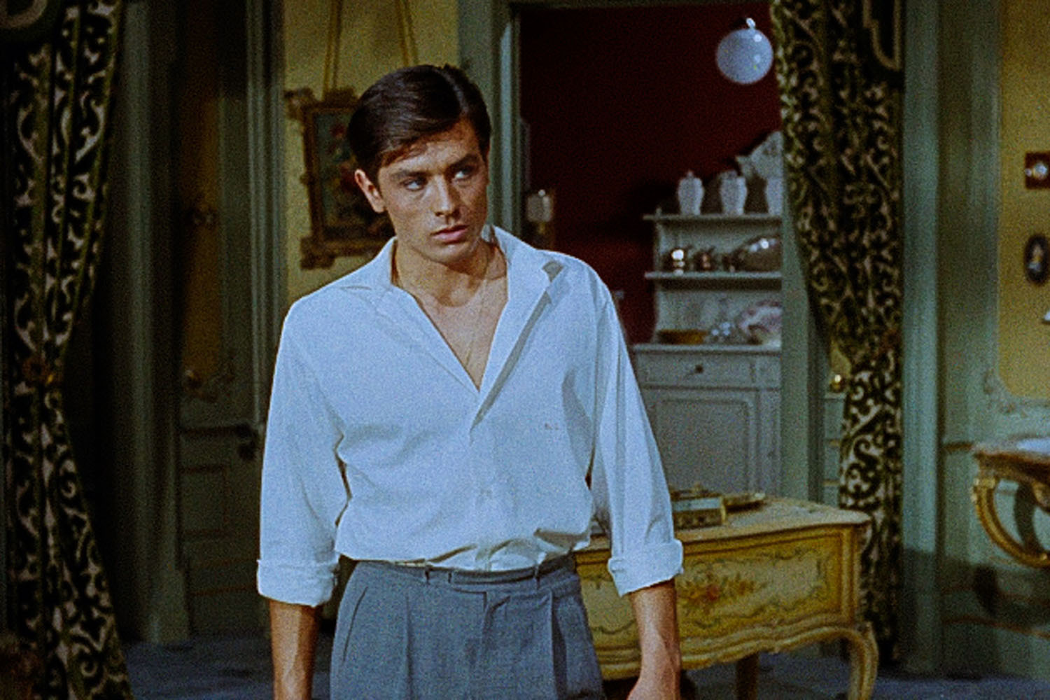 The actor Alain Delon in a blue button-up shirt with it opened slightly to show his chest
