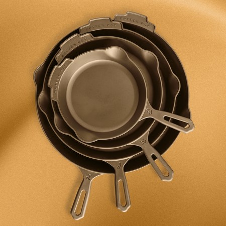 A stack of cast iron pans from Butter Pat Industries on a gold background