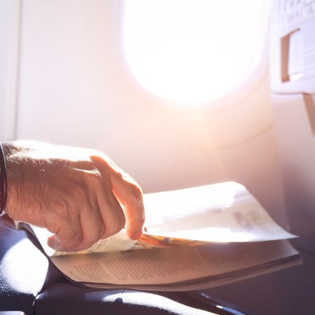 Man reading magazine in airplane - Close up shot of hand