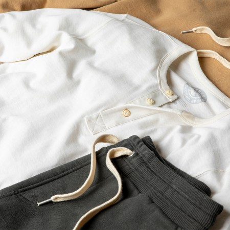 A white henley and grew sweatpants from Outerknown's Second Spin collection