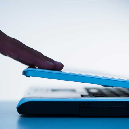 A hand closing a laptop computer