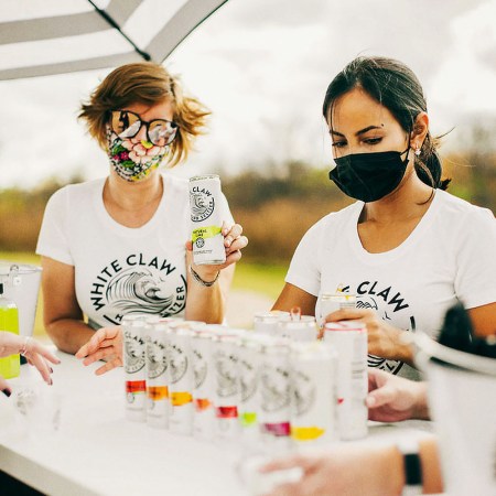 Three people serving White Claw at Seltzerland, a new traveling festival devoted to hard seltzers