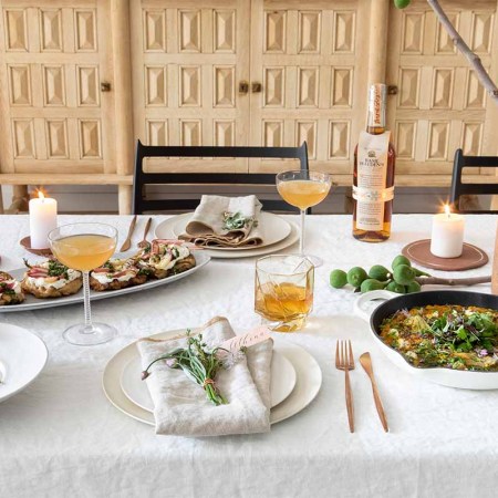 A table with brunch food, place settings, multiple cocktails and a bottle of Basil Hayden bourbon. Unconventional brunch drinks can improve your easy morning dining experience.
