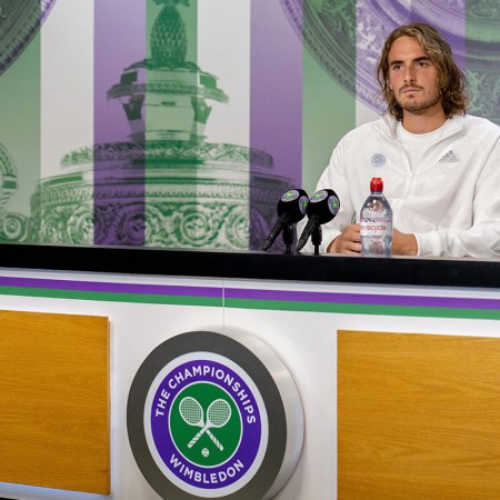 Pro tennis player Stefanos Tsitsipas sitting behind a table at Wimbledon and answering questions about why he won't take the COVID-19 vaccine