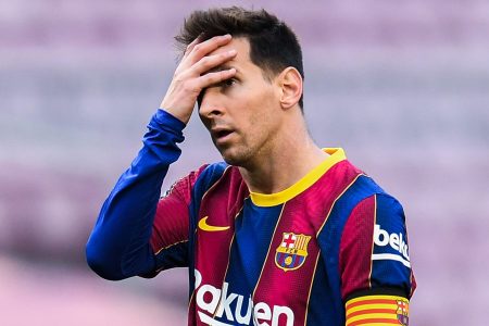 FC Barcelona star Lionel Messi holding his hand against his head. The soccer legend is out at the club after 17 seasons.