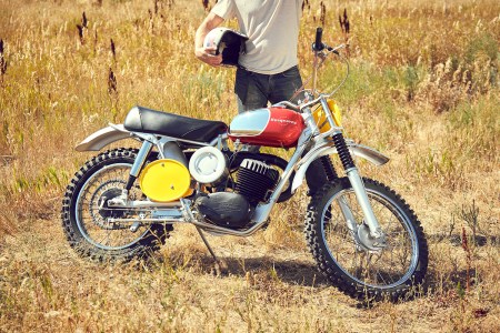 A man in a white T-shirt and blue jeans standing behind a 1968 Husqvarna Viking 360 that was owned by Steve McQueen. The motorcycle will sell at RM Sotheby's Monterey auction.