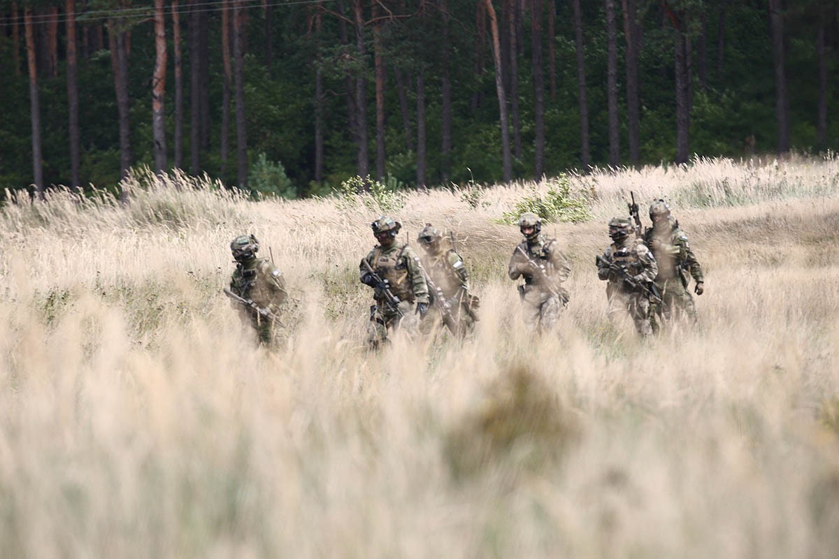 Special forces troops march through a field.