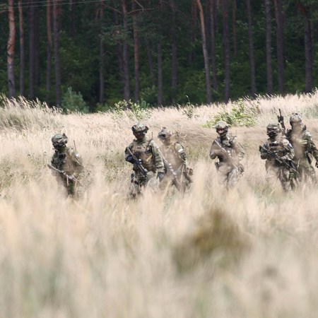 Special forces troops march through a field.