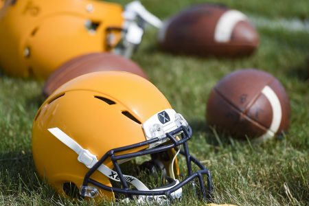 Football helmets and balls on the ground during a high school practice