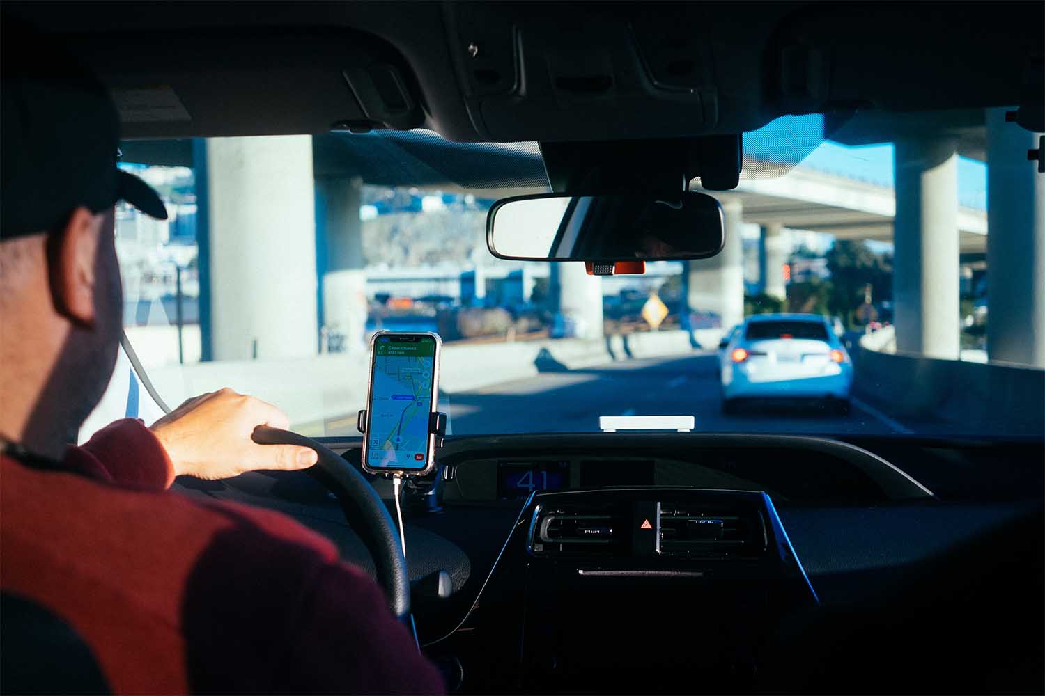 A Lyft driver in his car reading directions from his phone screen