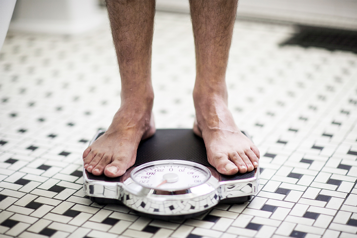 A man standing on a scale in the bathroom.