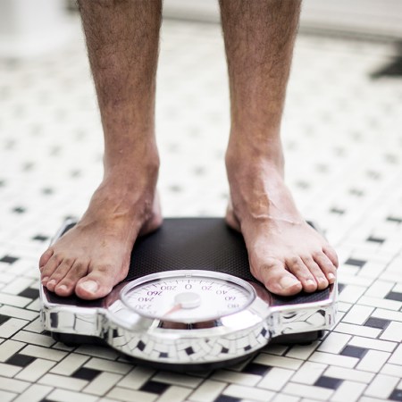 A man standing on a scale in the bathroom.