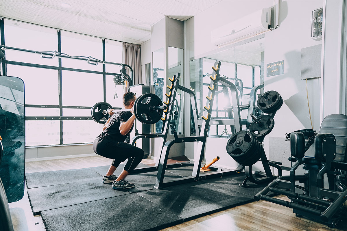 A man lifting a heavy barbell in a darkly lit gym.