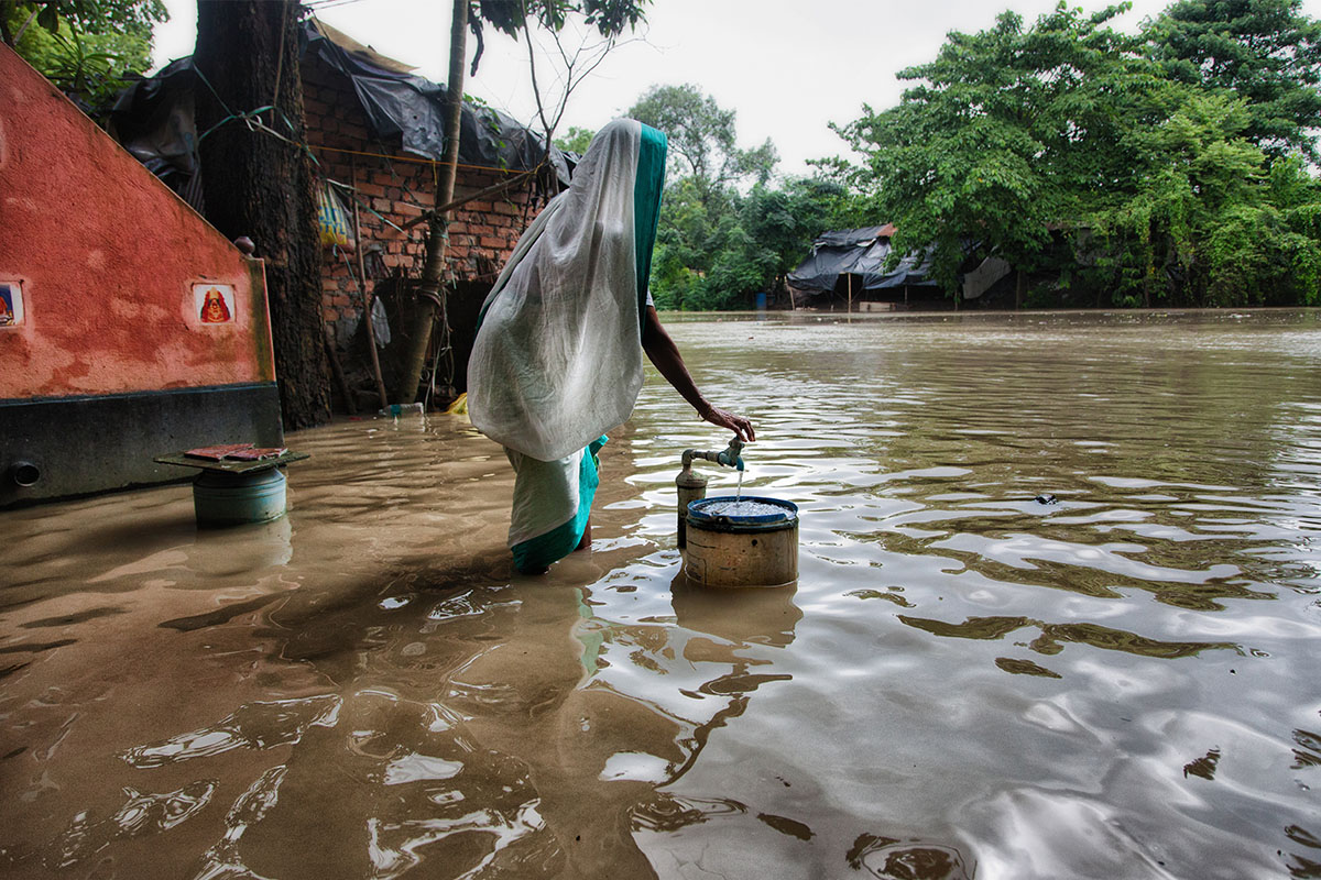 A woman scooping water into a bucket.