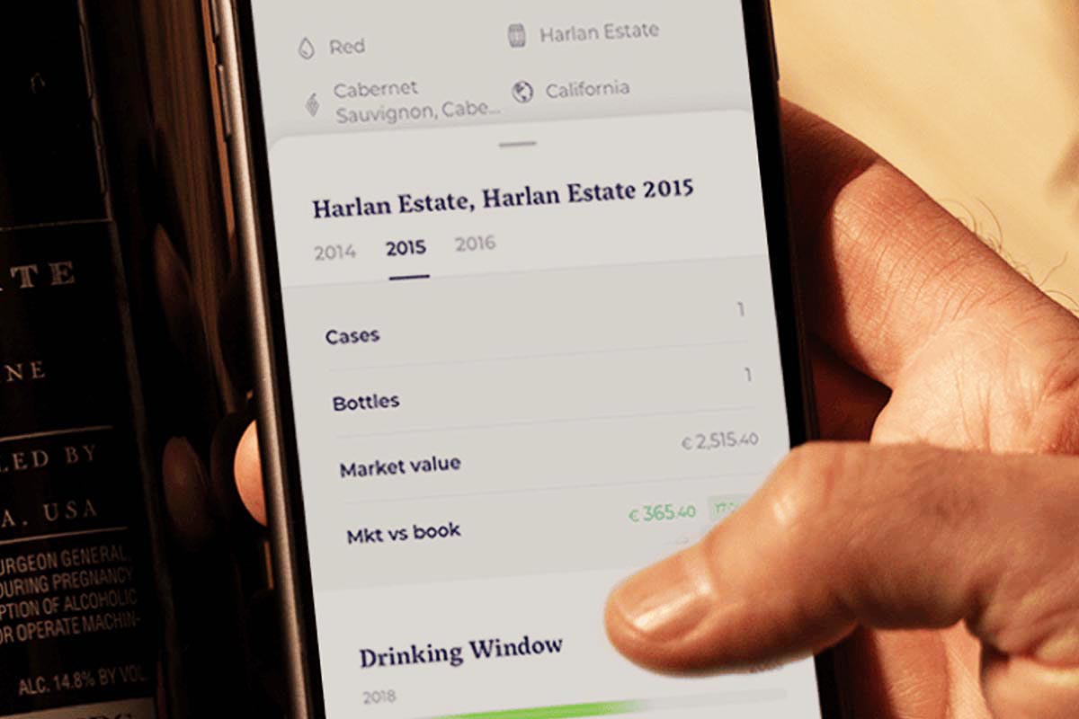A hand holding a phone with the 1275 wine collector's app open