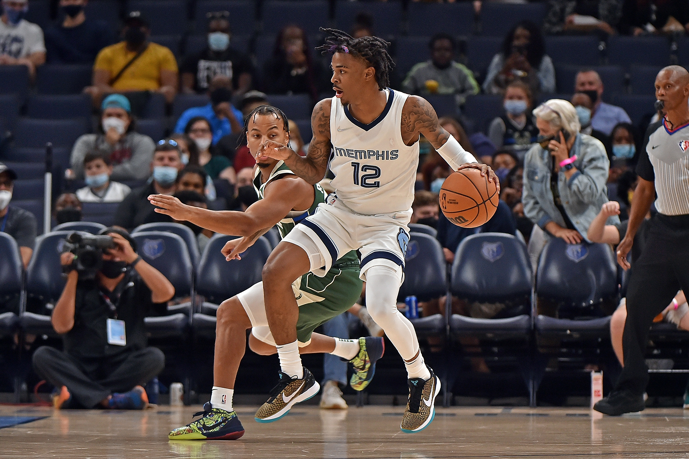 Ja Morant #12 of the Memphis Grizzlies handles the ball against Justin Robinson #55 of the Milwaukee Bucks during the first quarter during the preseason game at FedExForum on October 05, 2021 in Memphis, Tennessee.