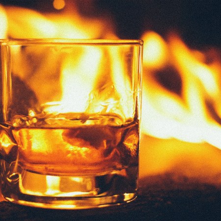 Smoky American whiskeys are a trend; pictured here, a glass of whiskey by a campfre