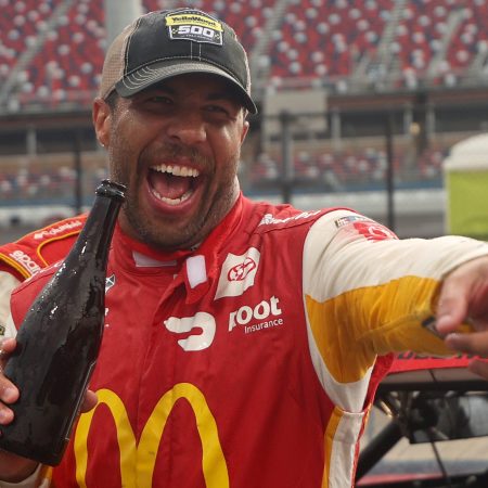 Bubba Wallace in red and yellow McDonald's branded livery celebrates after winning the rain-shortened NASCAR Cup Series YellaWood 500 at Talladega Superspeedway