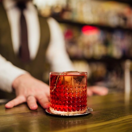 A bartender serving a single Negroni at a bar. Some bars specialize or focus on just one cocktail.