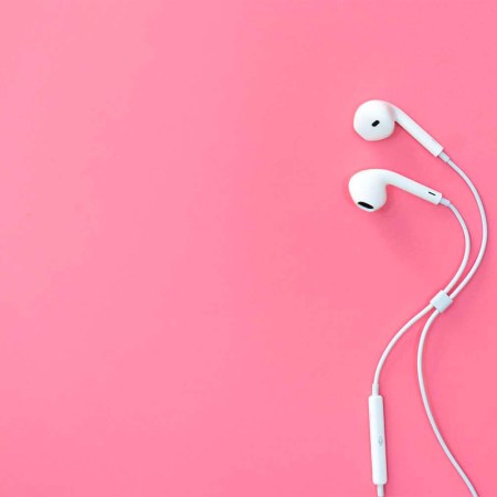 Apple wired headphones on a pink background.