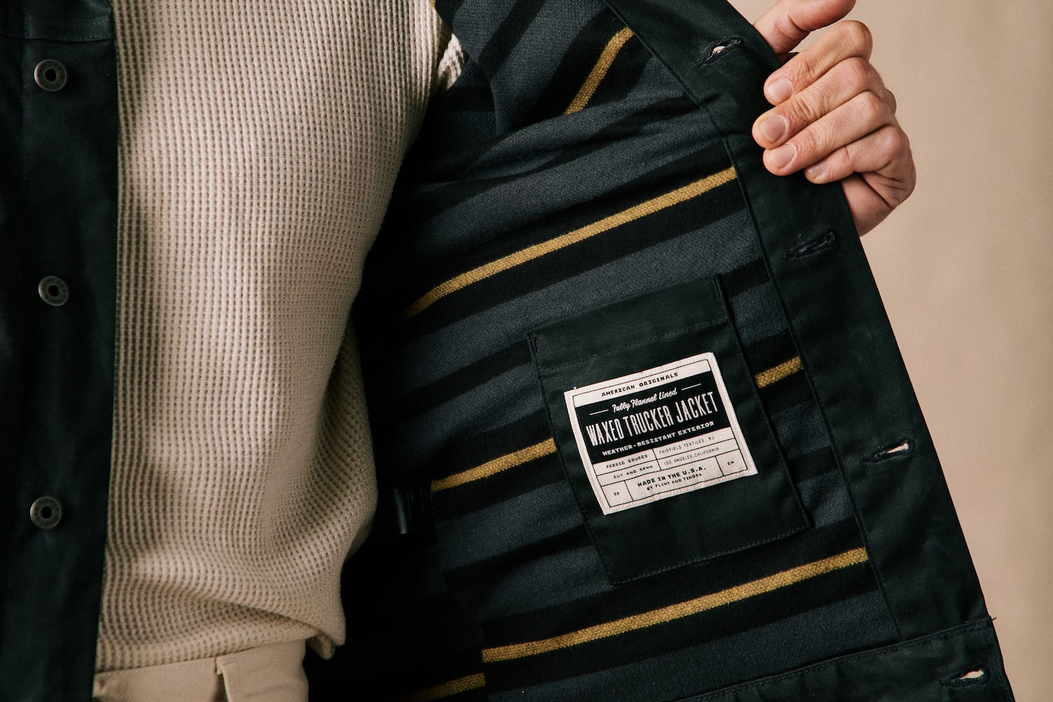 a model holding open a Flint and Tinder Waxed Trucker Jacket
