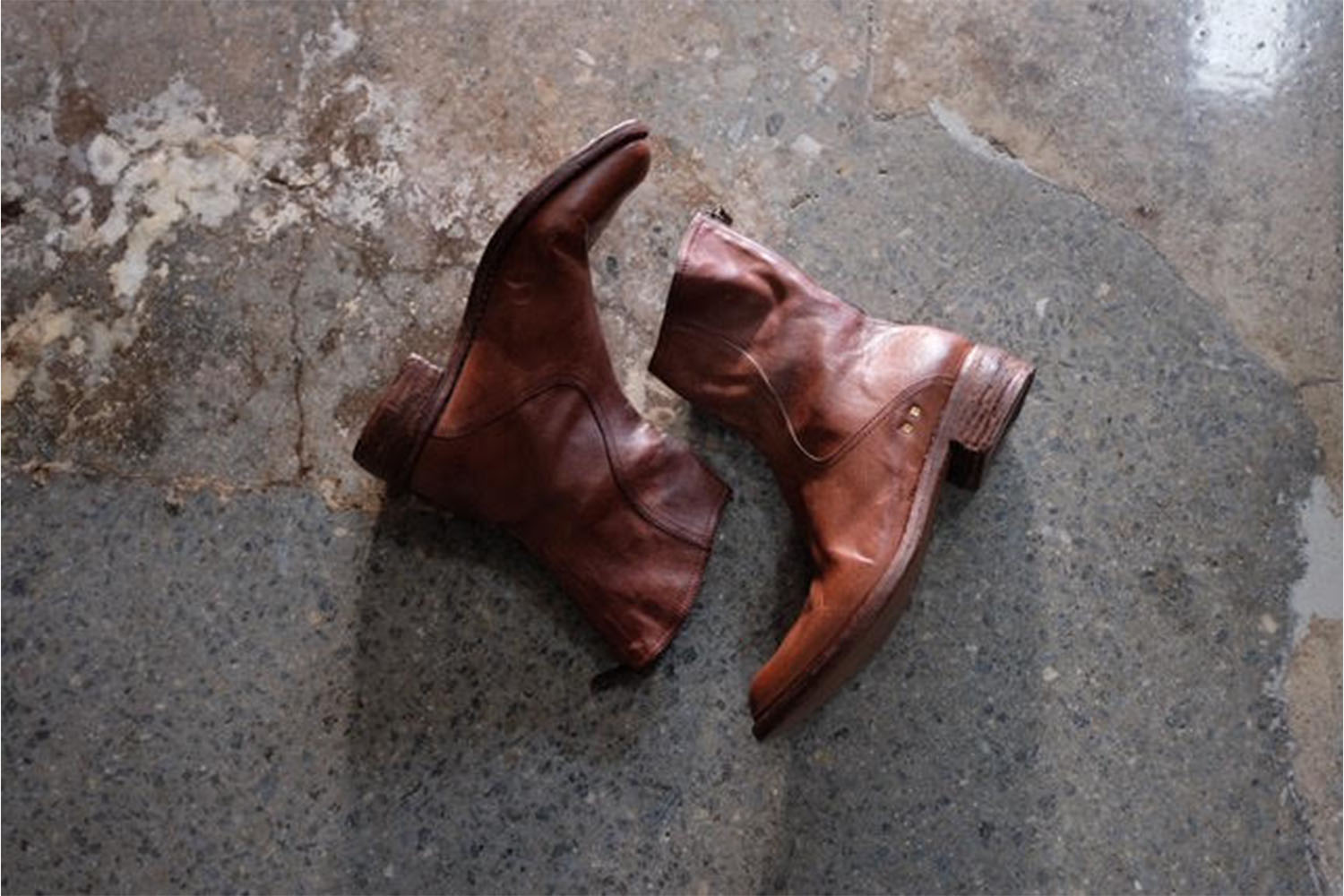 a pair of brown leather boots on concrete