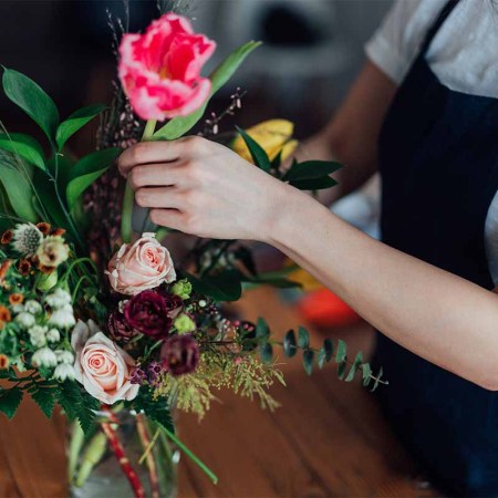 Cropped shot of young beautiful woman arranging fresh flowers in her living room.