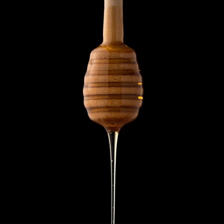 A honey dipper dripping with fresh honey. In 2022, consider replacing sugar with honey. Here's why.