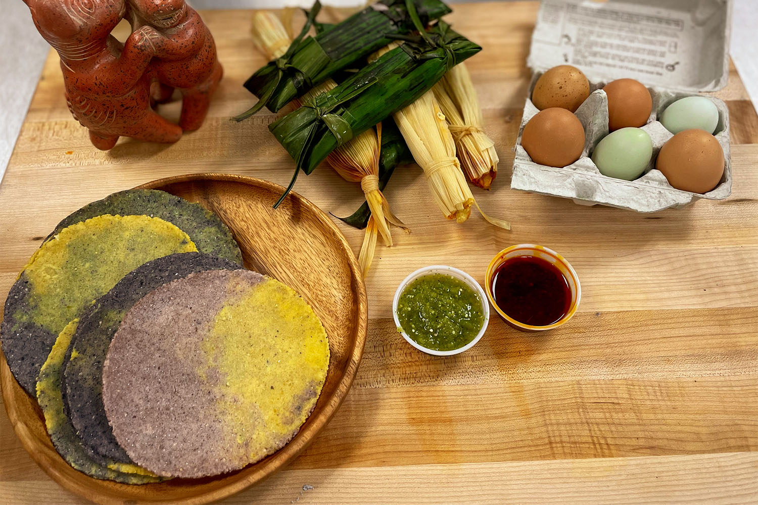 a counter full of tortillas, tamales, raw eggs, and sauces