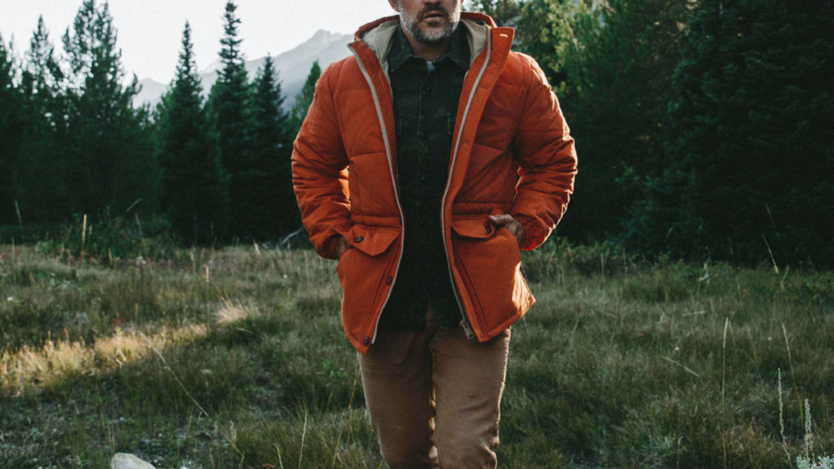 a model walking outdoors with the Taylor Stitch Whitney Parka and Camp Pants on