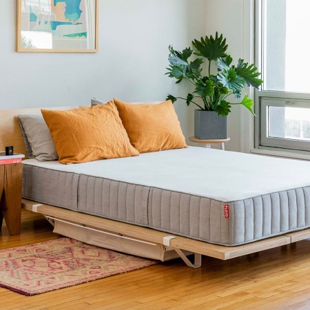 a mattress on a nice wooden frame in a minimal room