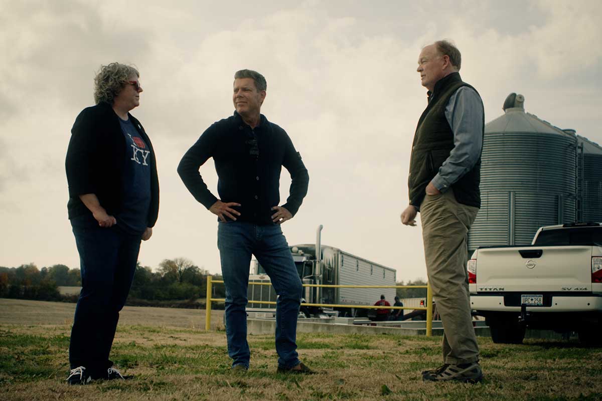 Three people in front of a distillery in the middle of a field, including CaskX founder Jeremy Kasler