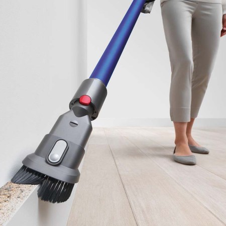 A Dyson vaccum being used on a wall by an unseen person. Dyson products are on sale at eBay.