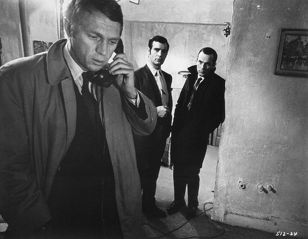 Bullitt (Steve McQueen) talks on the phone as 2 actors look on in a scene from the movie "Bullitt."