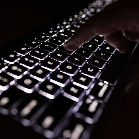 A man typing in the dark.