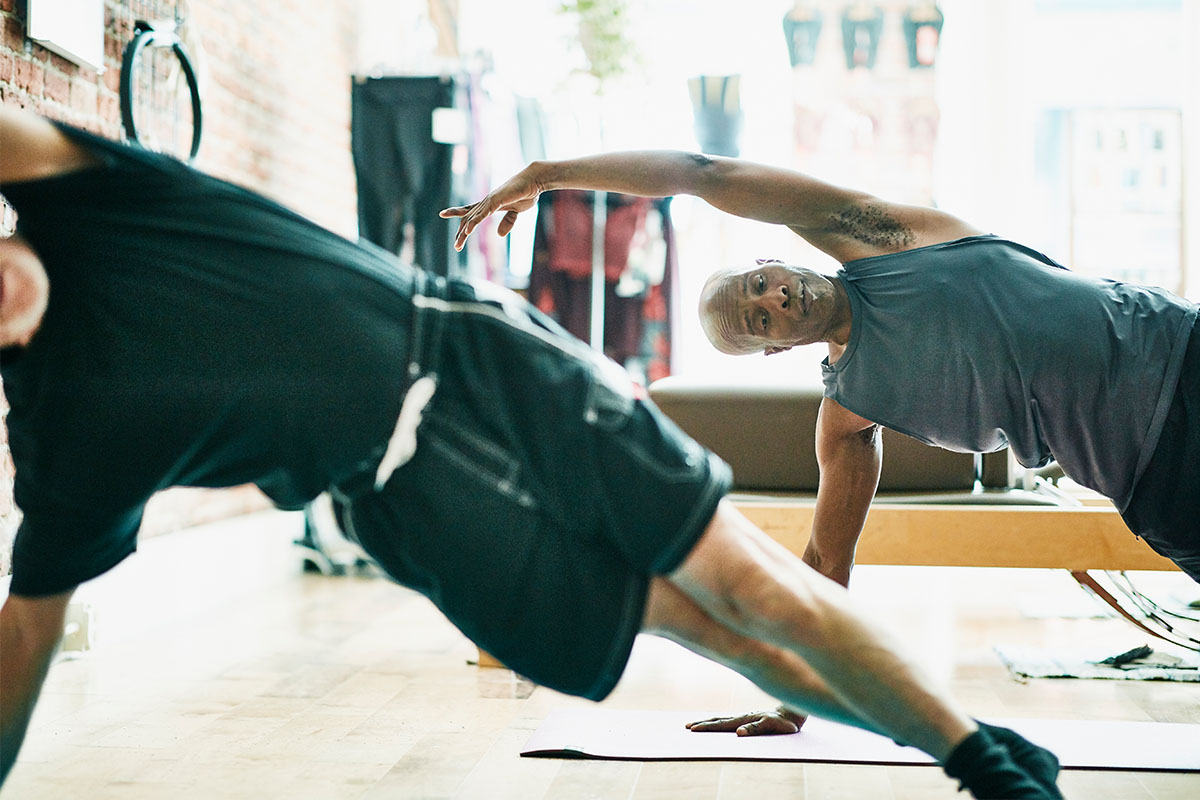Two men performing a side plank in a class. You know what exercise is even better? The Copenhagen plank.