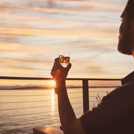 A man sitting near the water drinking whiskey on the rocks and looking at the sky. The concept of "smooth" as an adjective in whisky is contentious.