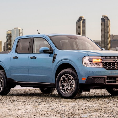 The 2022 Ford Maverick in blue sitting in front of a city skyline. We tested and reviewed the pickup and found a lot to love.