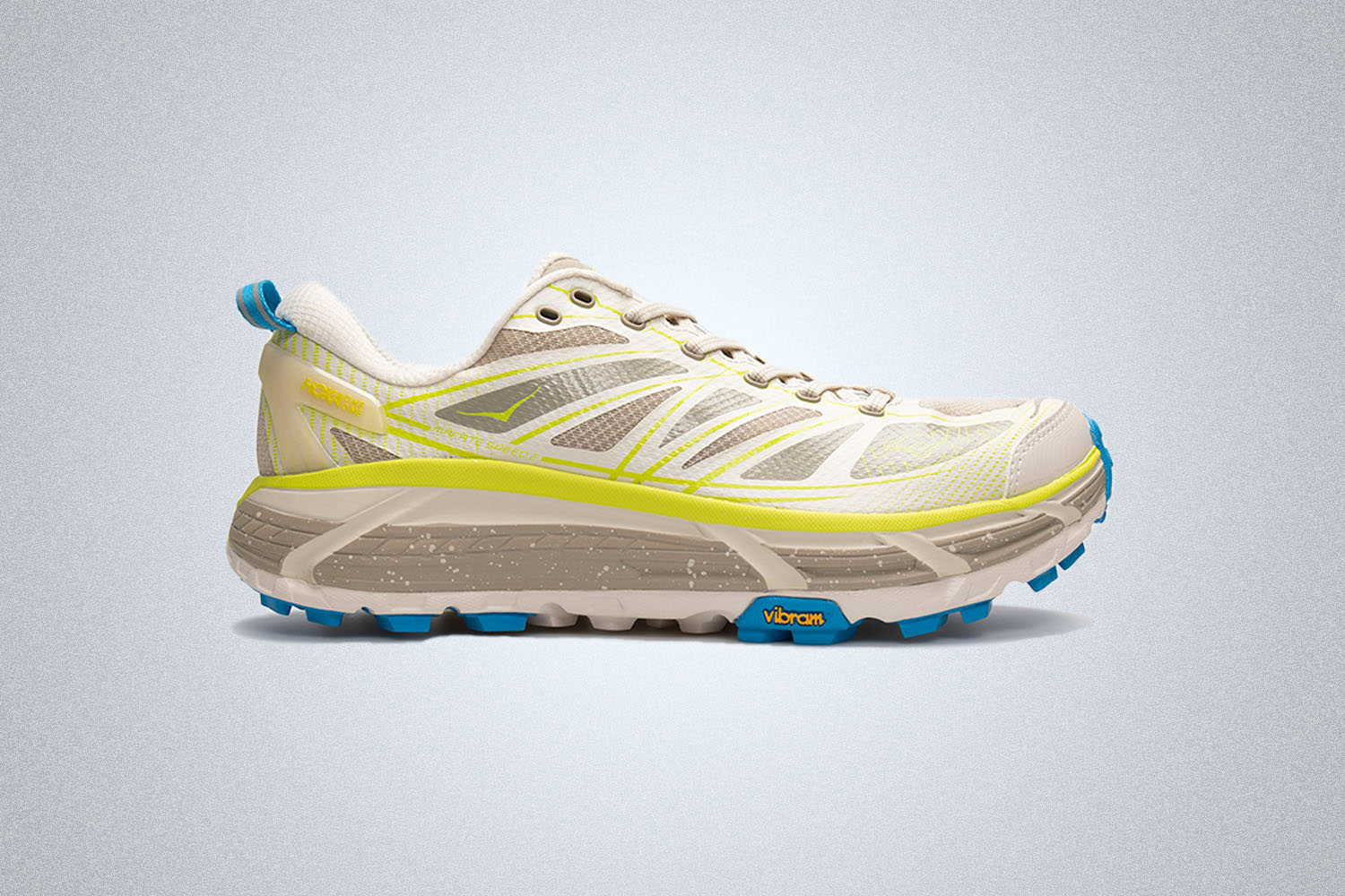 a beige, cream, white, and yellow Hoka sneaker on a grey background