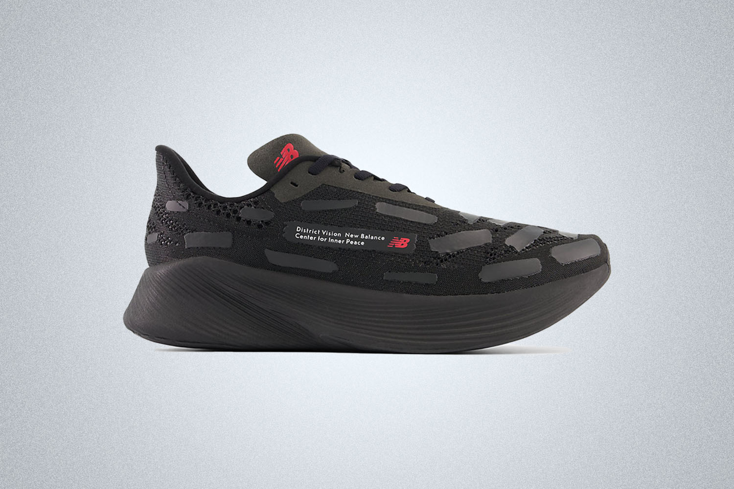 a large-soled, all black running shoe from New Balance x District Vision on a grey background
